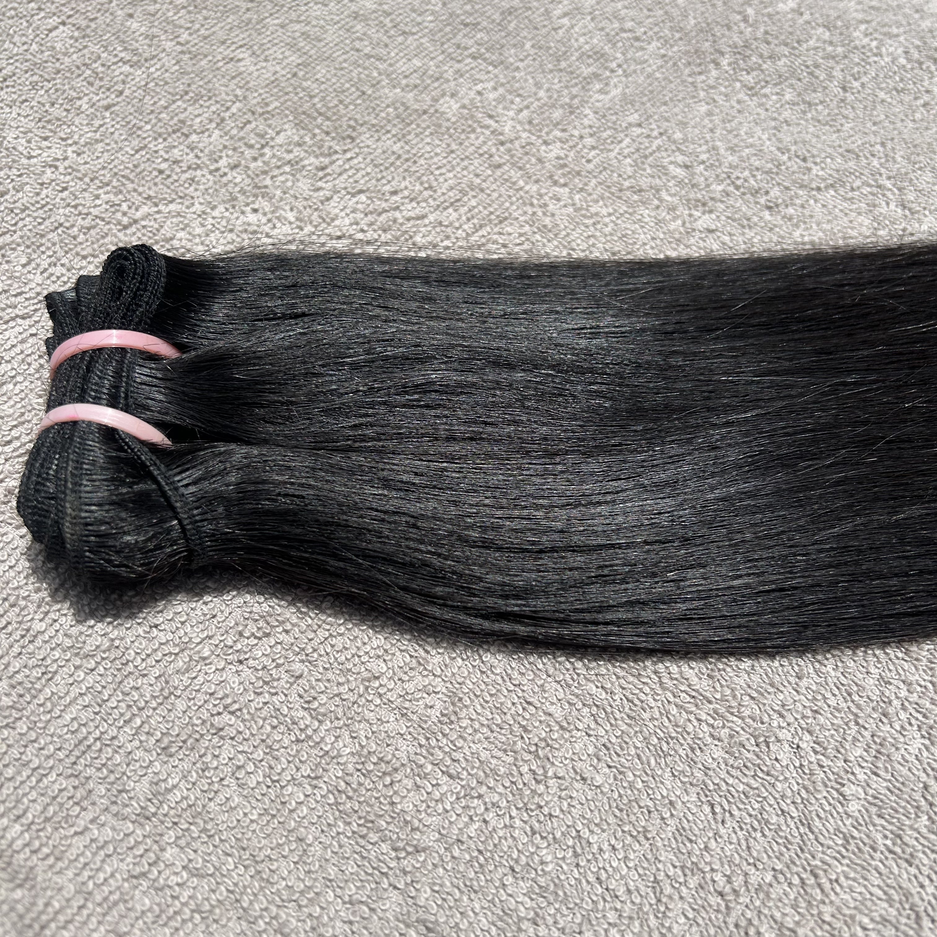 Bundle of black hair extensions on a gray surface