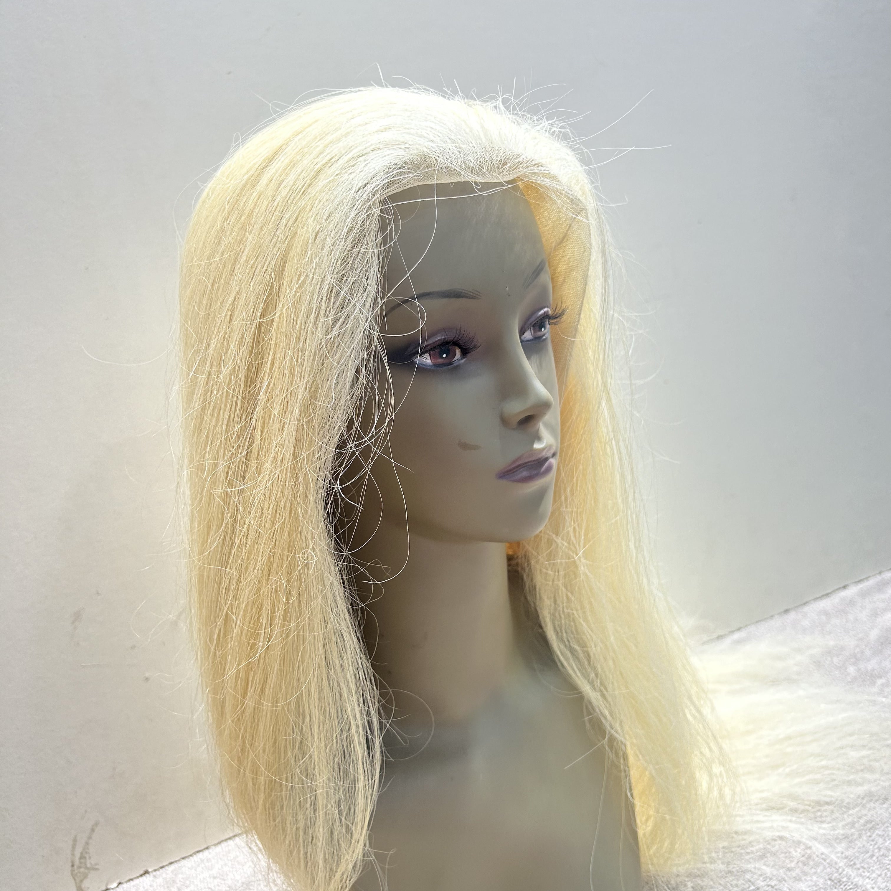 Blonde wig on a mannequin head against a plain background