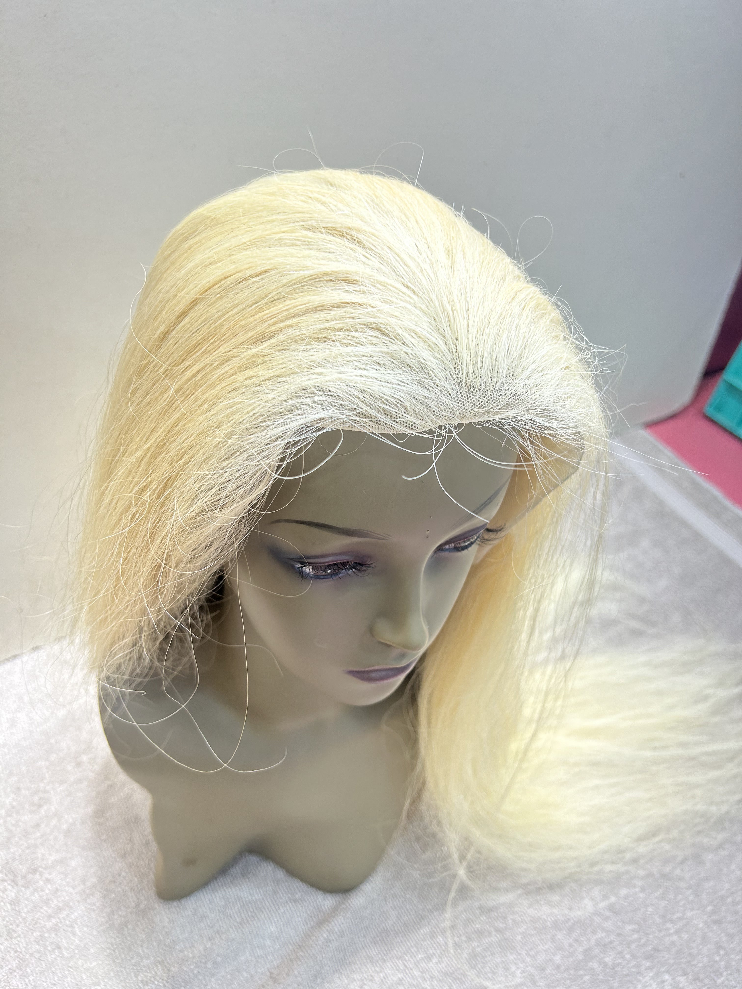 Blonde wig on a mannequin head against a plain background
