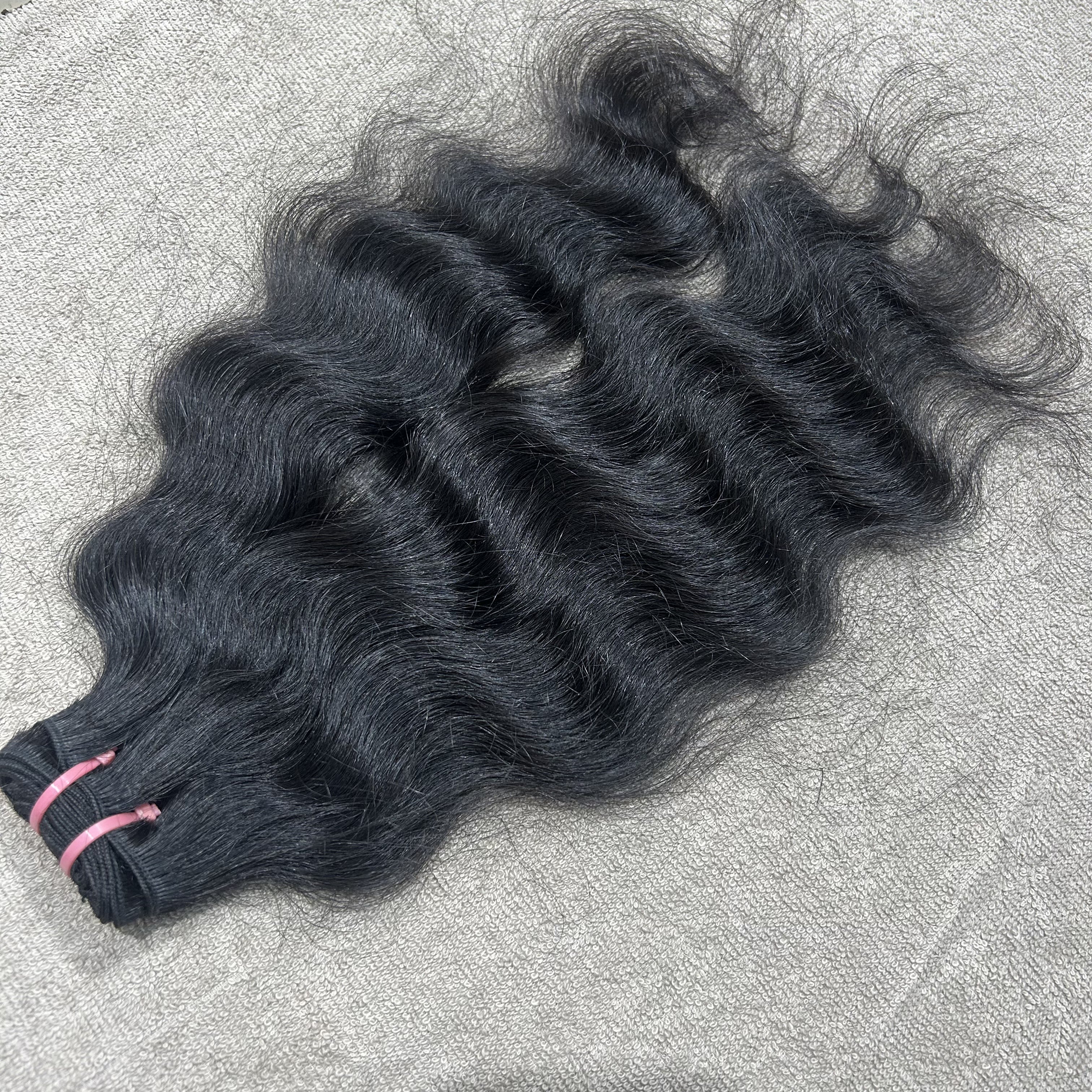 Three bundles of wavy black hair on a textured gray surface