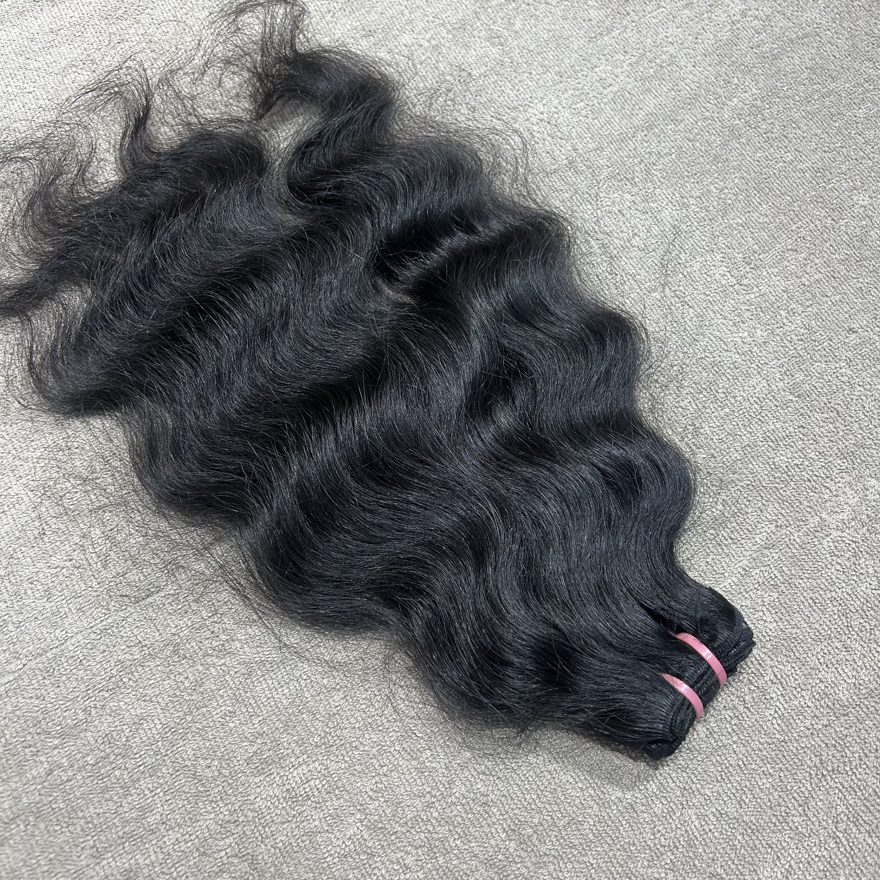 Black hair extensions on a gray surface
