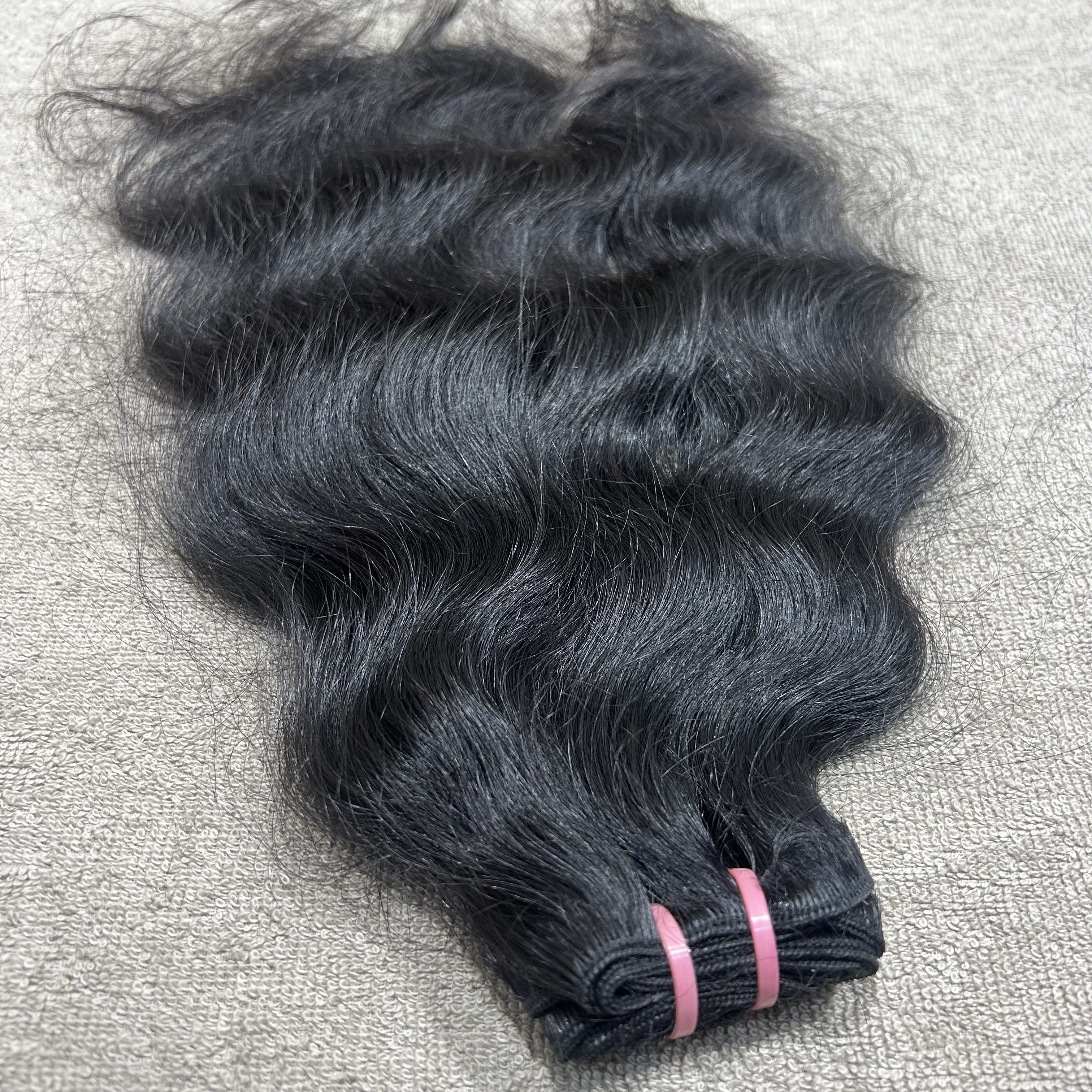 Bundle of black hair extensions on a textured gray surface