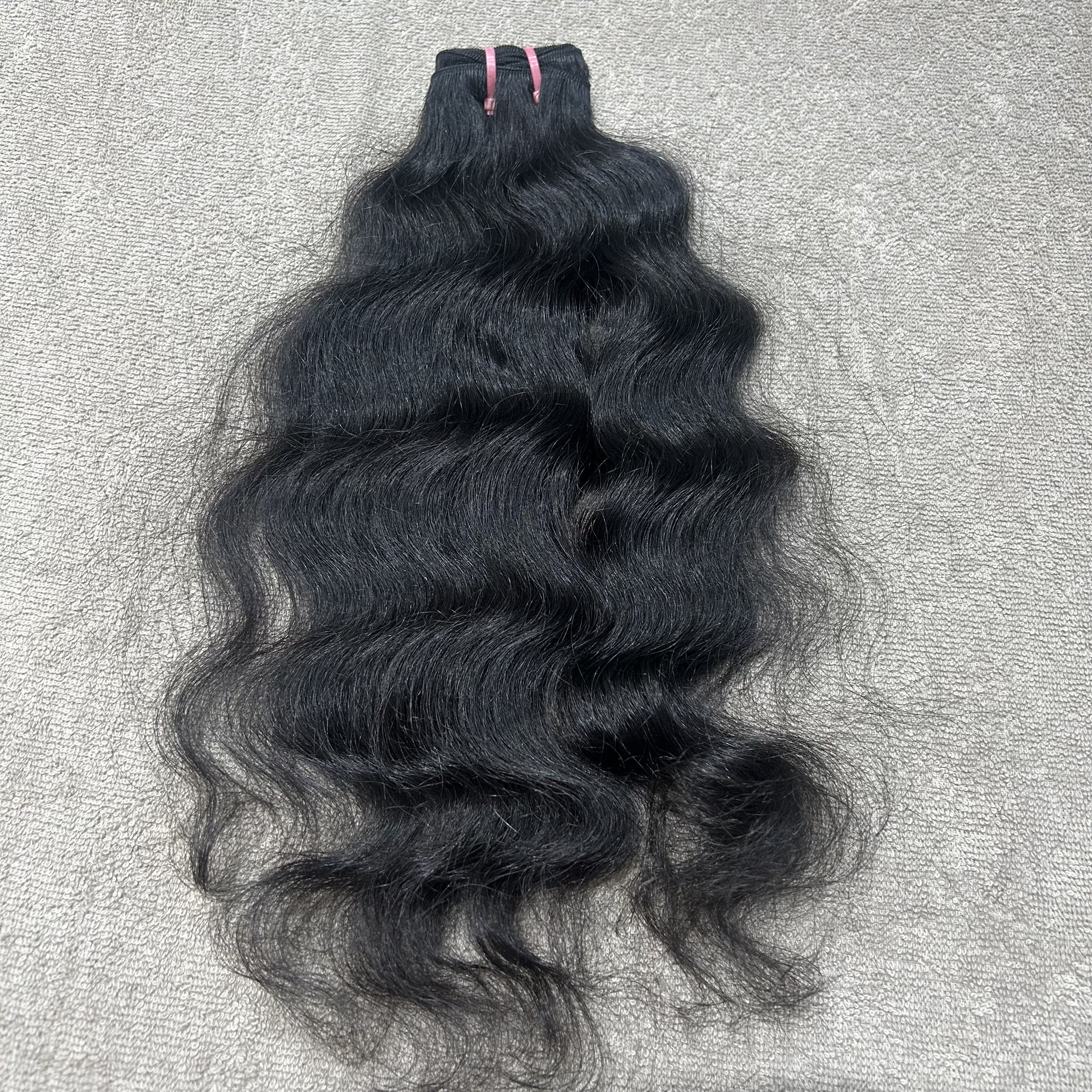 Black wavy hair bundle on a gray textured background