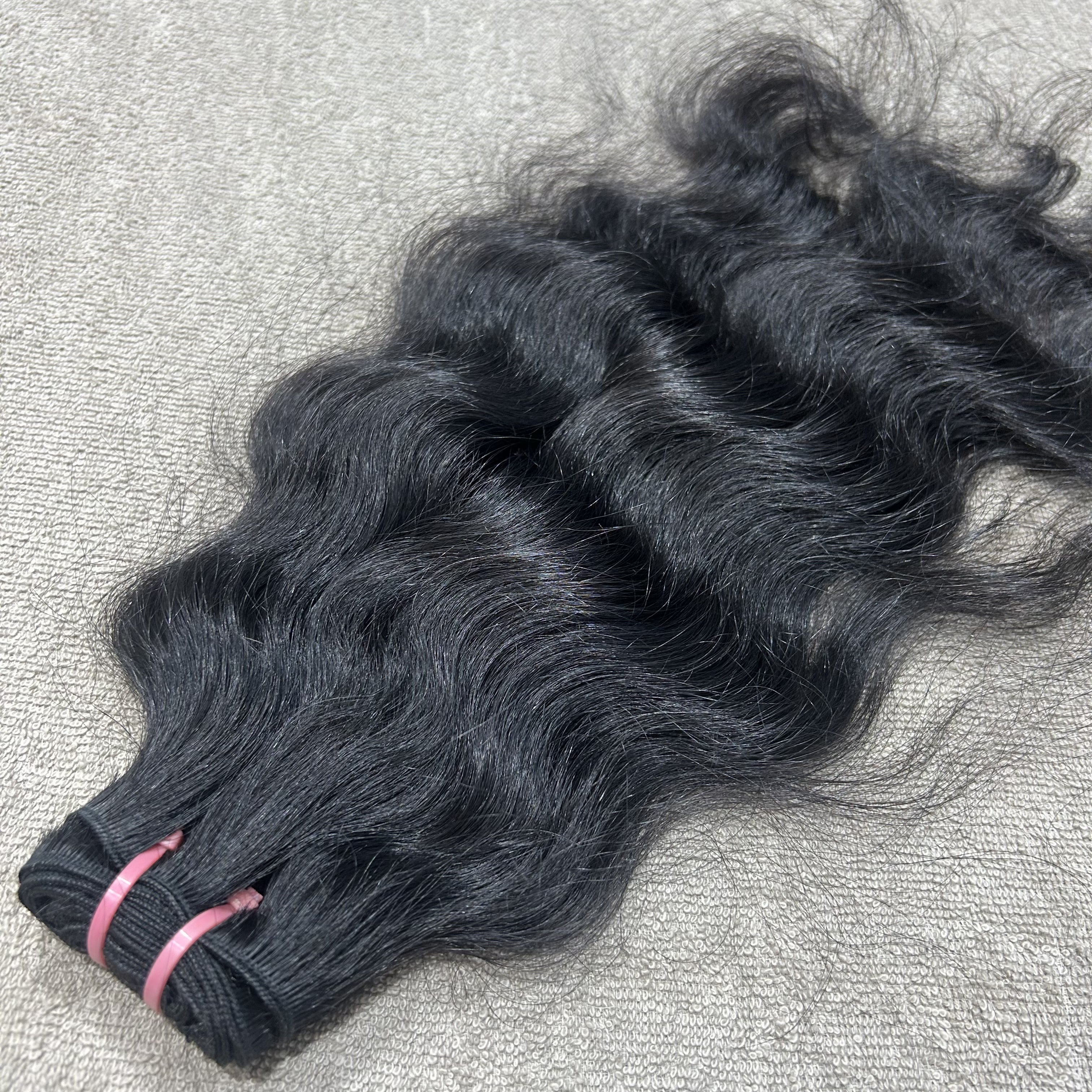 Bundles of black hair extensions on a textured surface