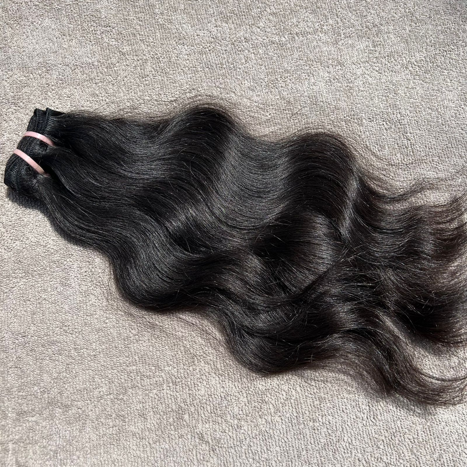 Black hair extensions on a gray surface