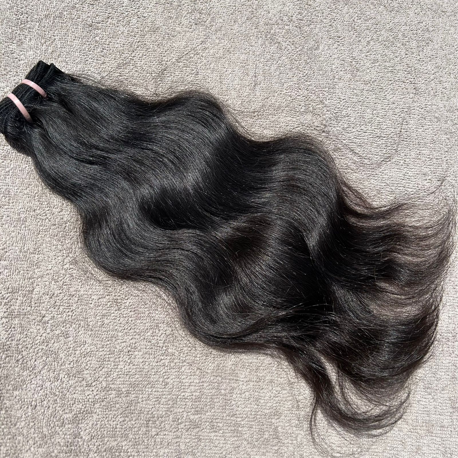Black hair extensions on a gray surface